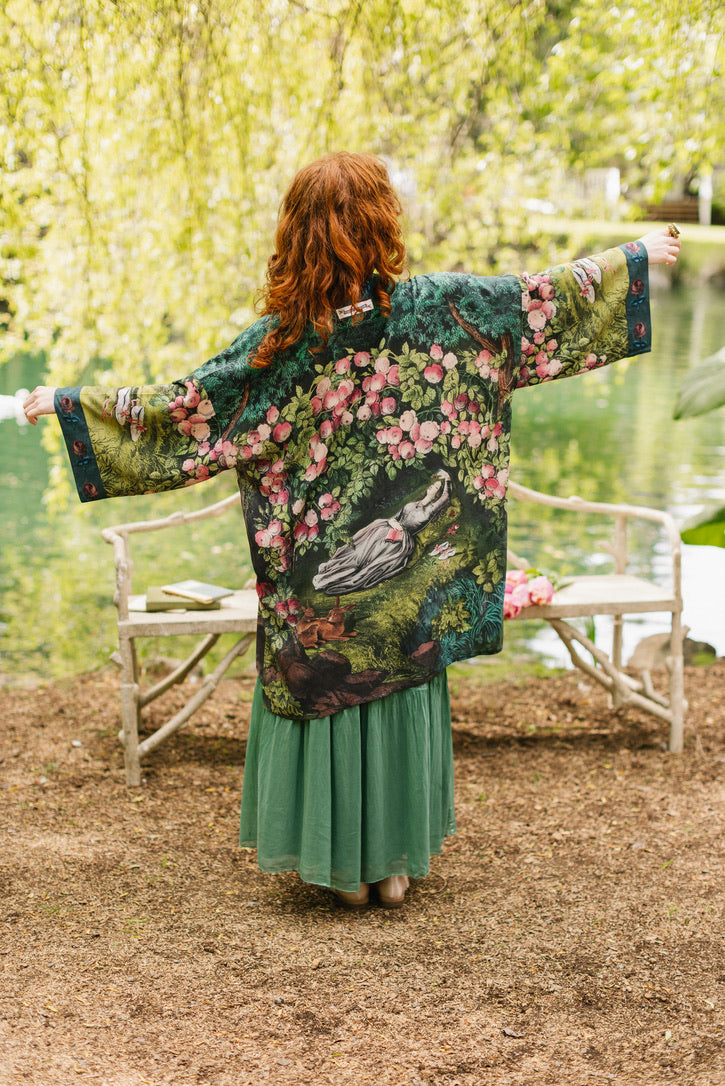 Woman wearing a floral kimono with her arms outstretched in a garden setting